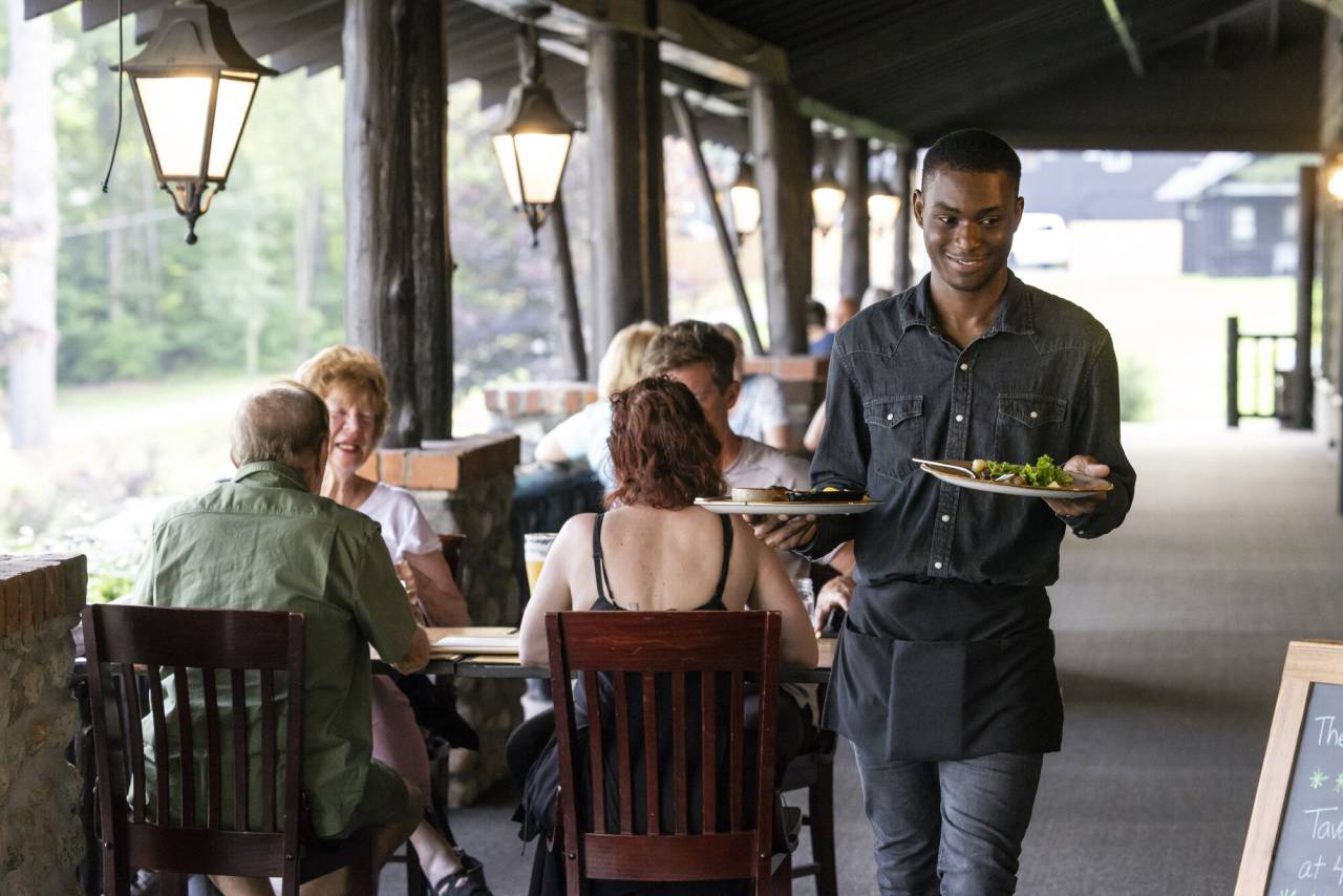 A waiter takes food from a table at a lodge. 